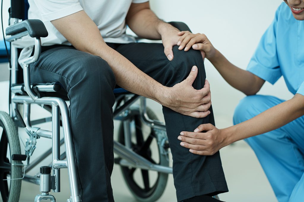 A healthcare professional examining a patient’s knee to assess pain and mobility issues caused by a bone chip in the knee at Dr. Burke Orthopedics in Houston.